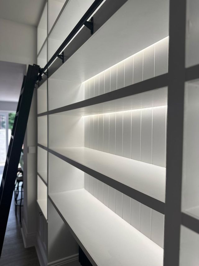 Close view of lit shelves with tongue-and-groove back panels and a ladder rail