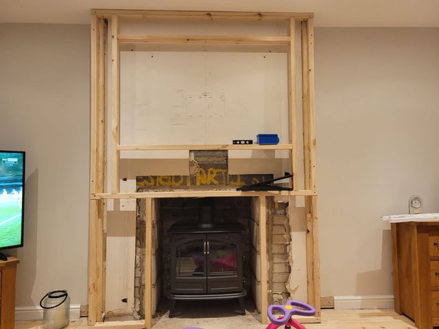Timber stud frame for a media wall built around a stove-style fire