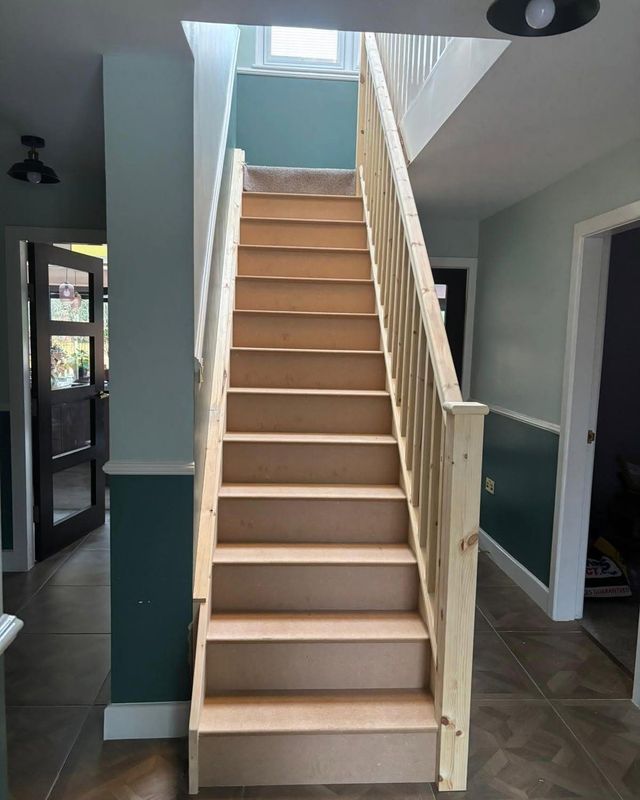 New pine staircase with square spindles and a newel post, fitted in a hallway before finishing
