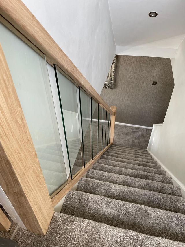 Oak-clad newel post, oak handrail and glass panels on a renovated staircase