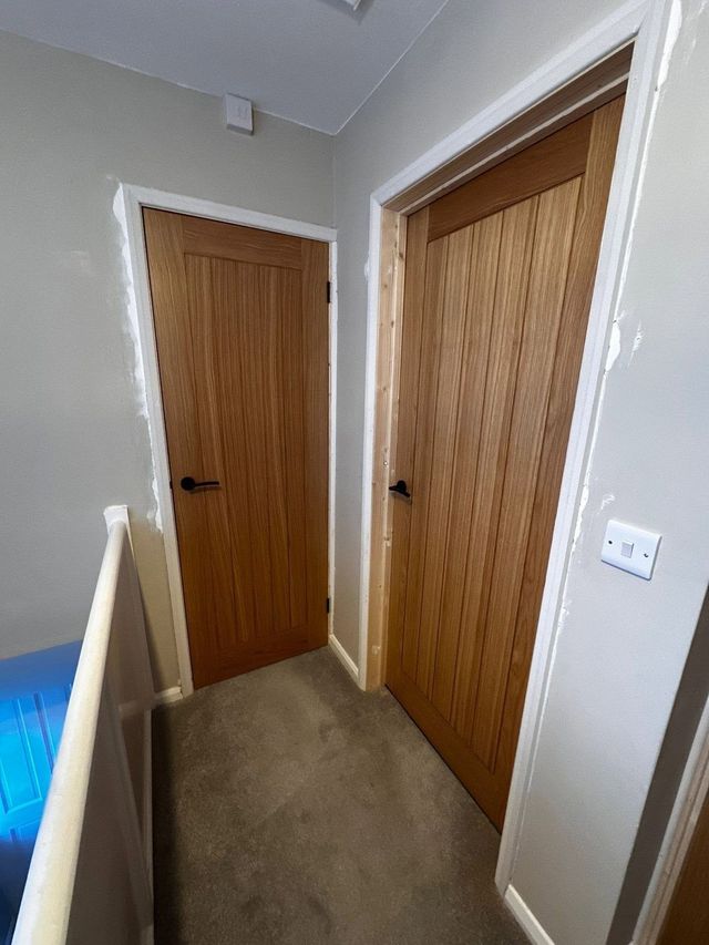 Oak cottage-style internal doors with black lever handles fitted on a landing