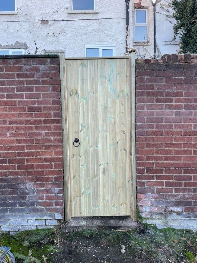 Outside face of a tongue and groove wooden gate between brick walls
