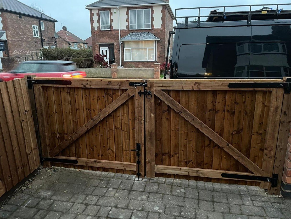 Pair of stained timber driveway gates closed across a block-paved drive