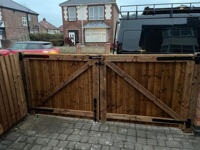 Pair of stained timber driveway gates closed across a block-paved drive