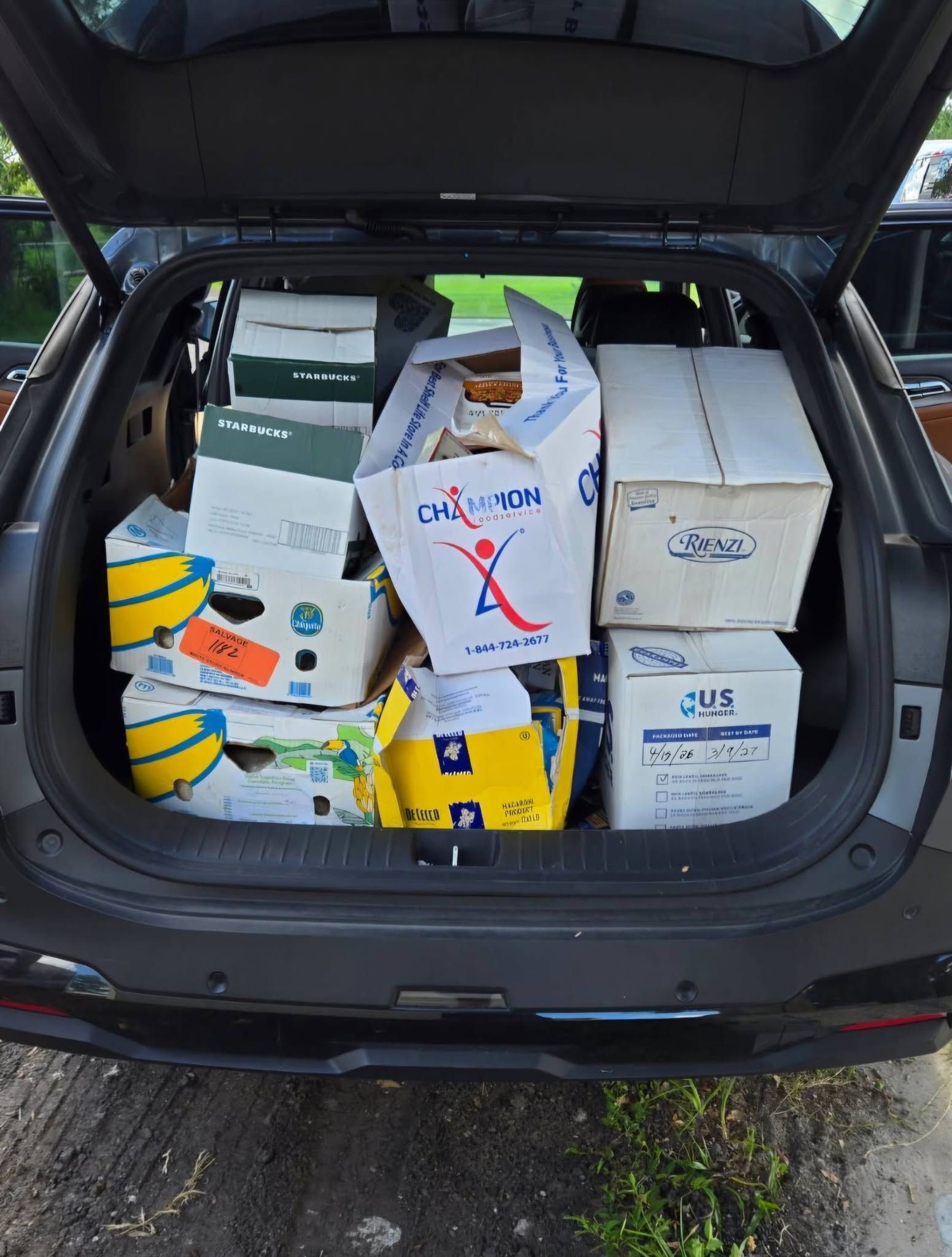 Open SUV trunk packed with stacked cardboard boxes and supplies.