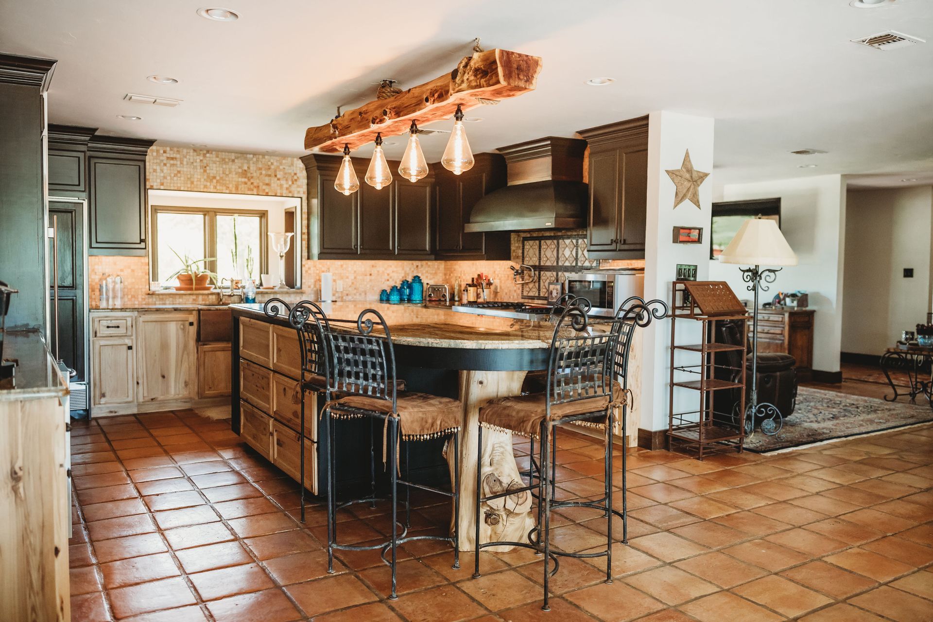 A kitchen with a large island and stools in it.