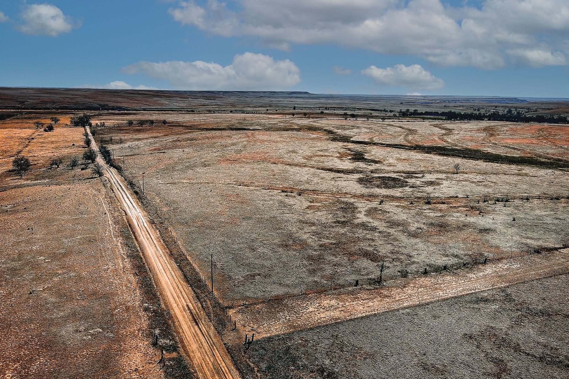 An aerial view of a dirt road going through a desert landscape.
