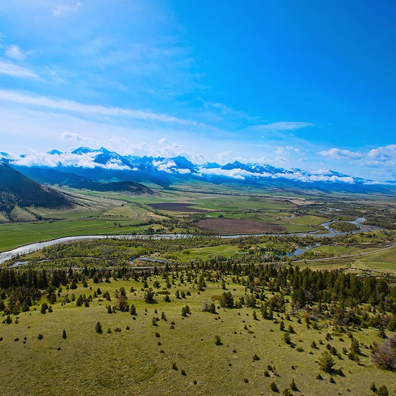 An aerial view of a lush green valley with mountains in the background.