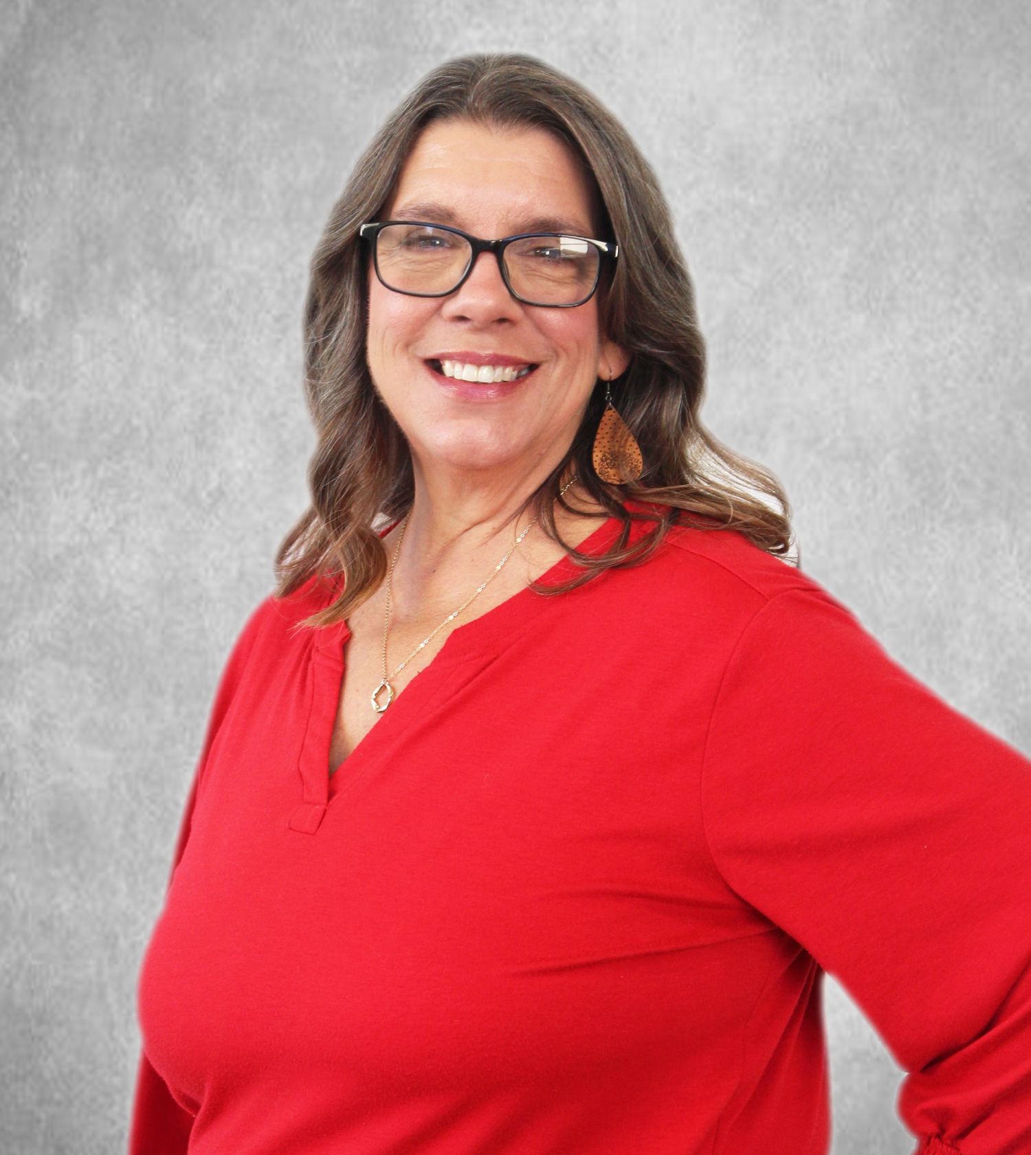 Smiling person in glasses wearing a red top against a gray backdrop