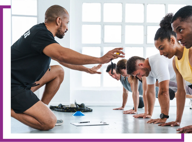 Fitness trainer coaching a group in plank position during a workout class