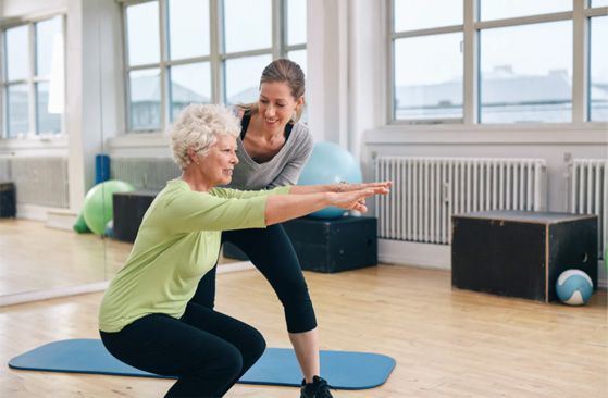 Physical therapist assisting a woman with squat exercises in a bright studio