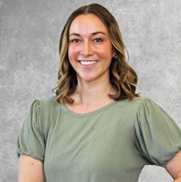 Smiling woman in a green puff-sleeve top against a gray background