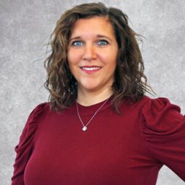 Smiling woman in a burgundy top against a gray background