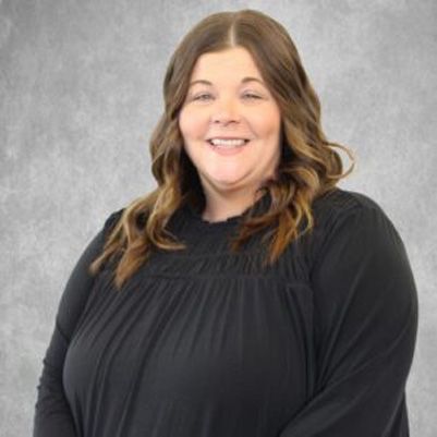 Smiling woman in a black top against a gray studio background