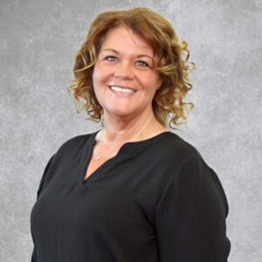 Smiling woman in a black top against a gray studio backdrop