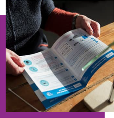 Person holding open a blue-and-white brochure on a wooden table