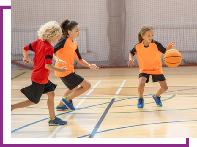 Three children playing basketball indoors, dribbling and running on a gym floor