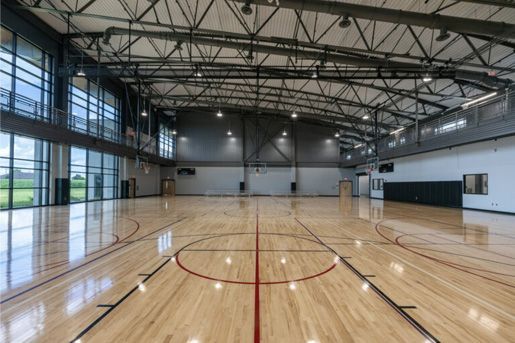 Empty indoor basketball court with polished wood floor and high metal ceiling