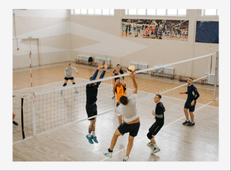 Volleyball players jumping at the net in a bright indoor gym during a rally