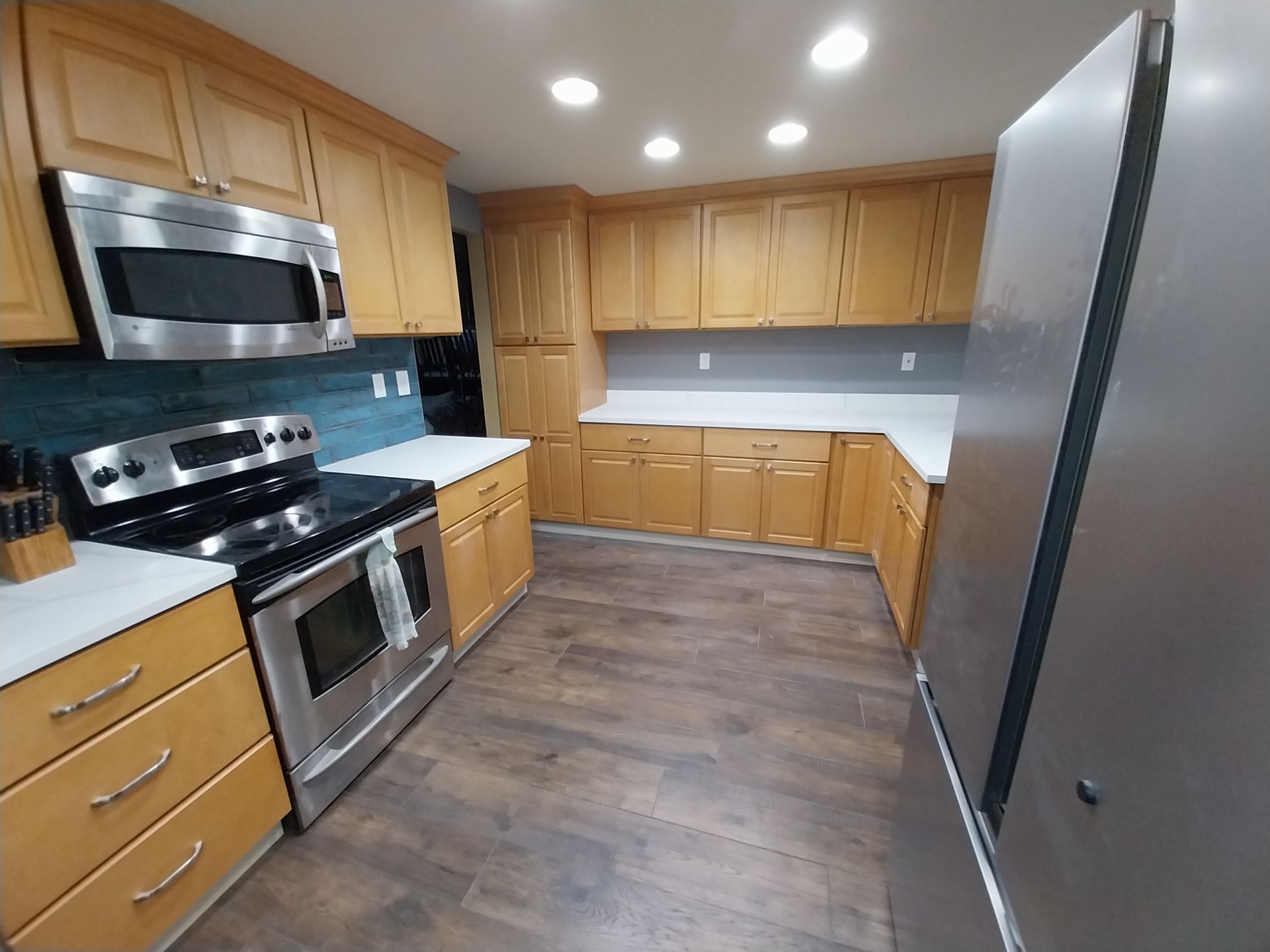 Modern kitchen with wood cabinets, stainless steel appliances, and dark flooring