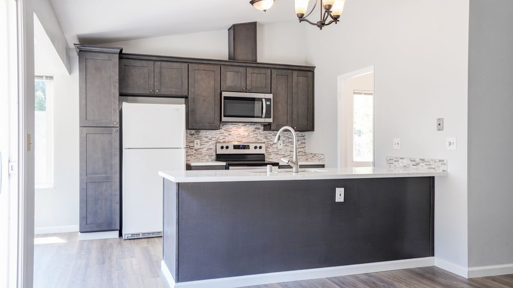 Modern kitchen with dark cabinets, white appliances, and a gray island in an open room