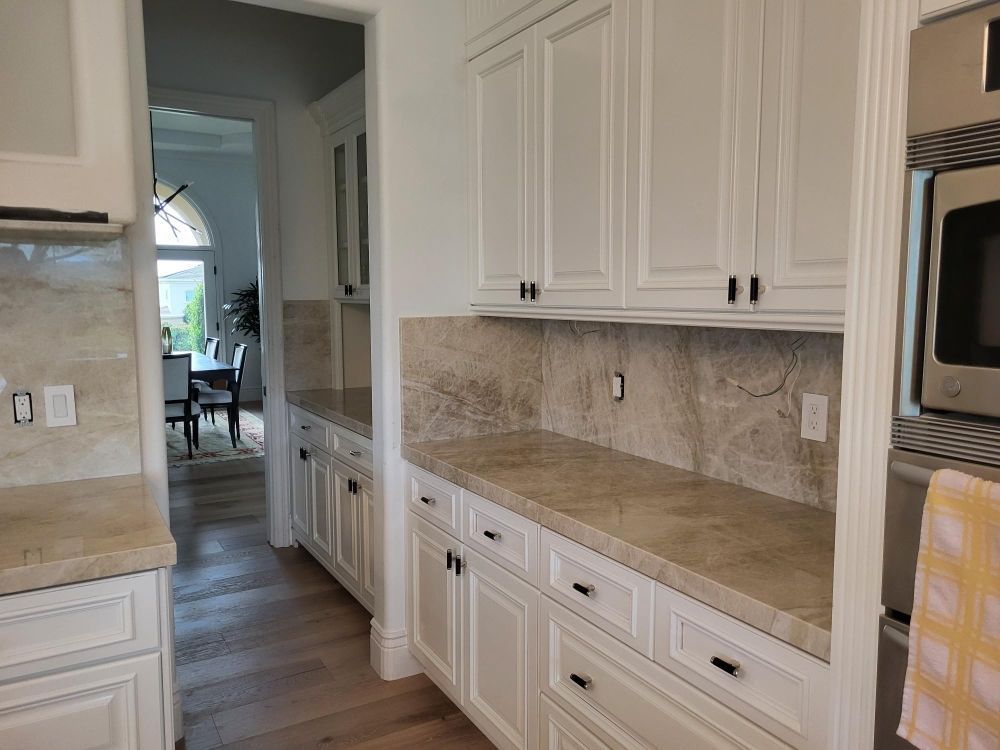 Bright kitchen with white cabinets, beige counters, and a doorway to a dining area