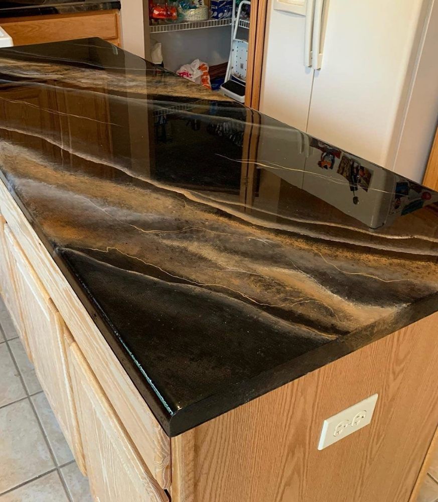 Black and brown marble-look countertop on a light wood kitchen island with cabinets underneath