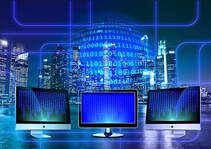 Picture of 3 computer display screens with computing numbers displayed in the background.