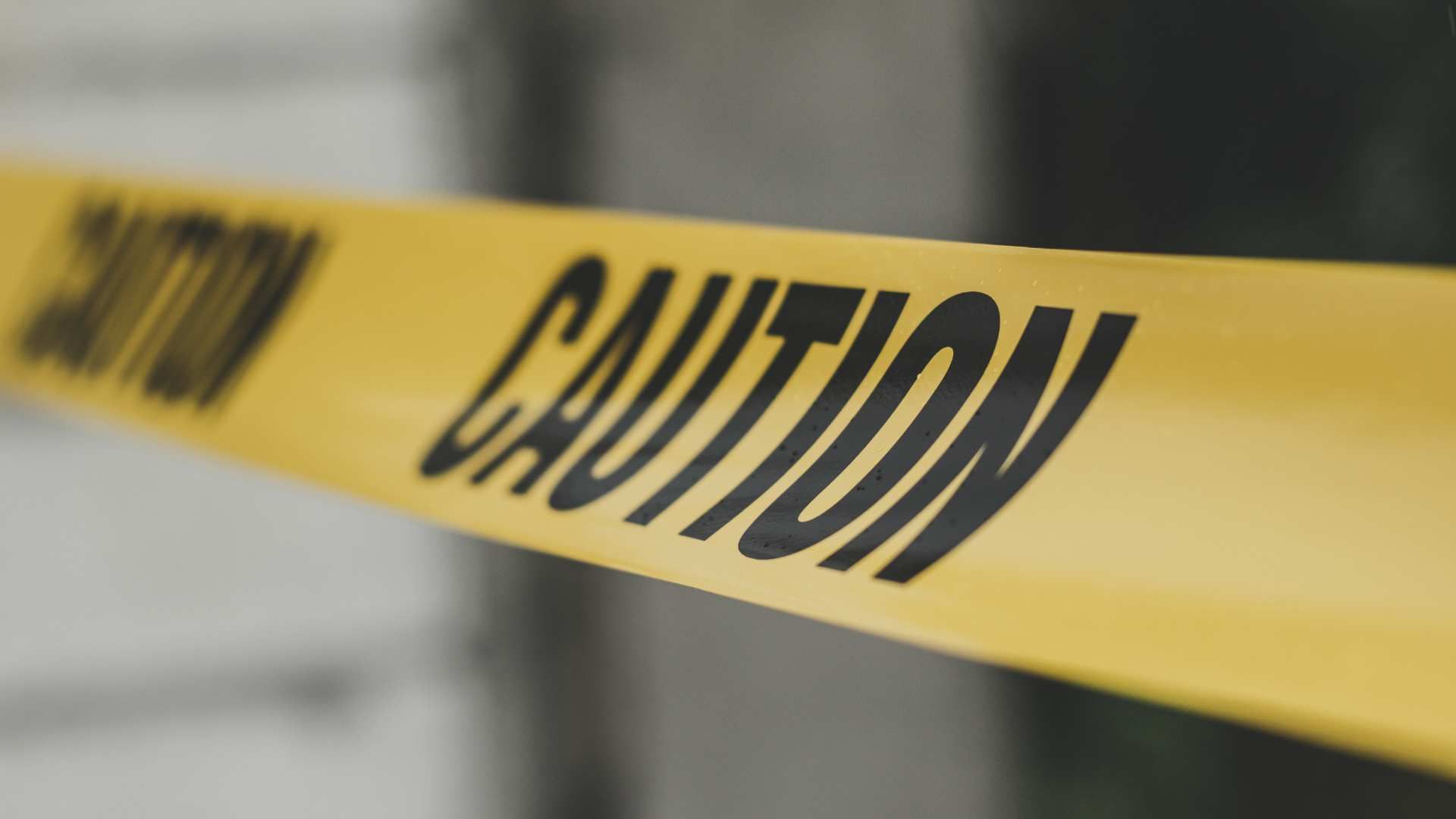 Yellow caution tape stretched across a blurred background.