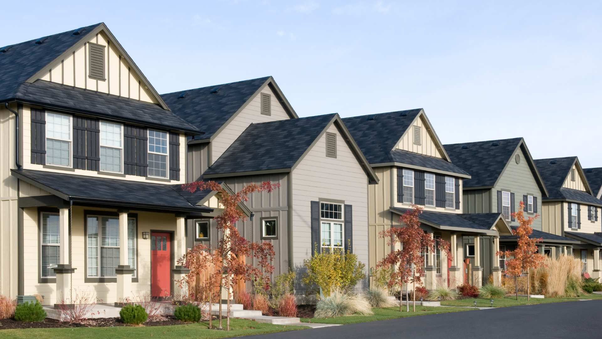 Row of modern suburban townhouses with gray siding and gabled roofs along a street