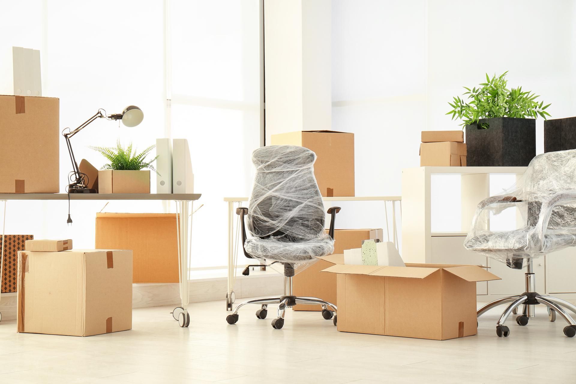Boxes and furniture being moved in a brightly lit office space.