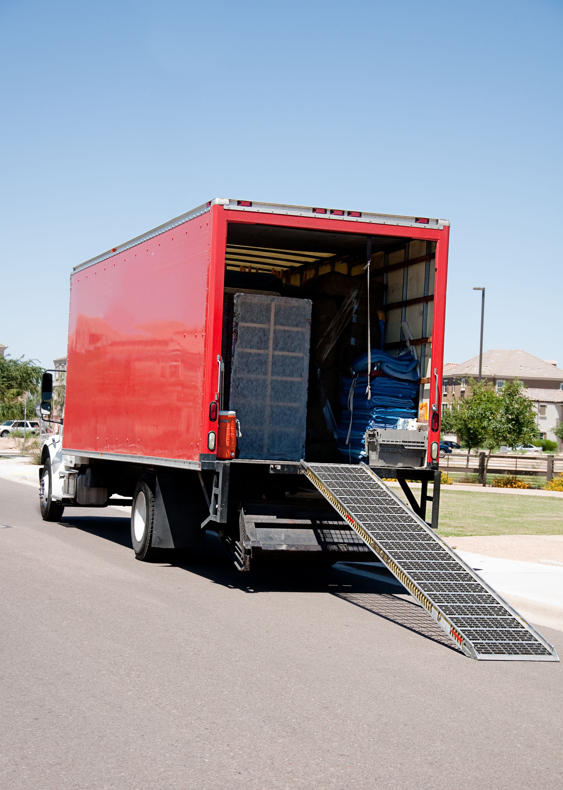 Movers Silverdale WA loading a red moving truck with ramp down in a residential neighborhood