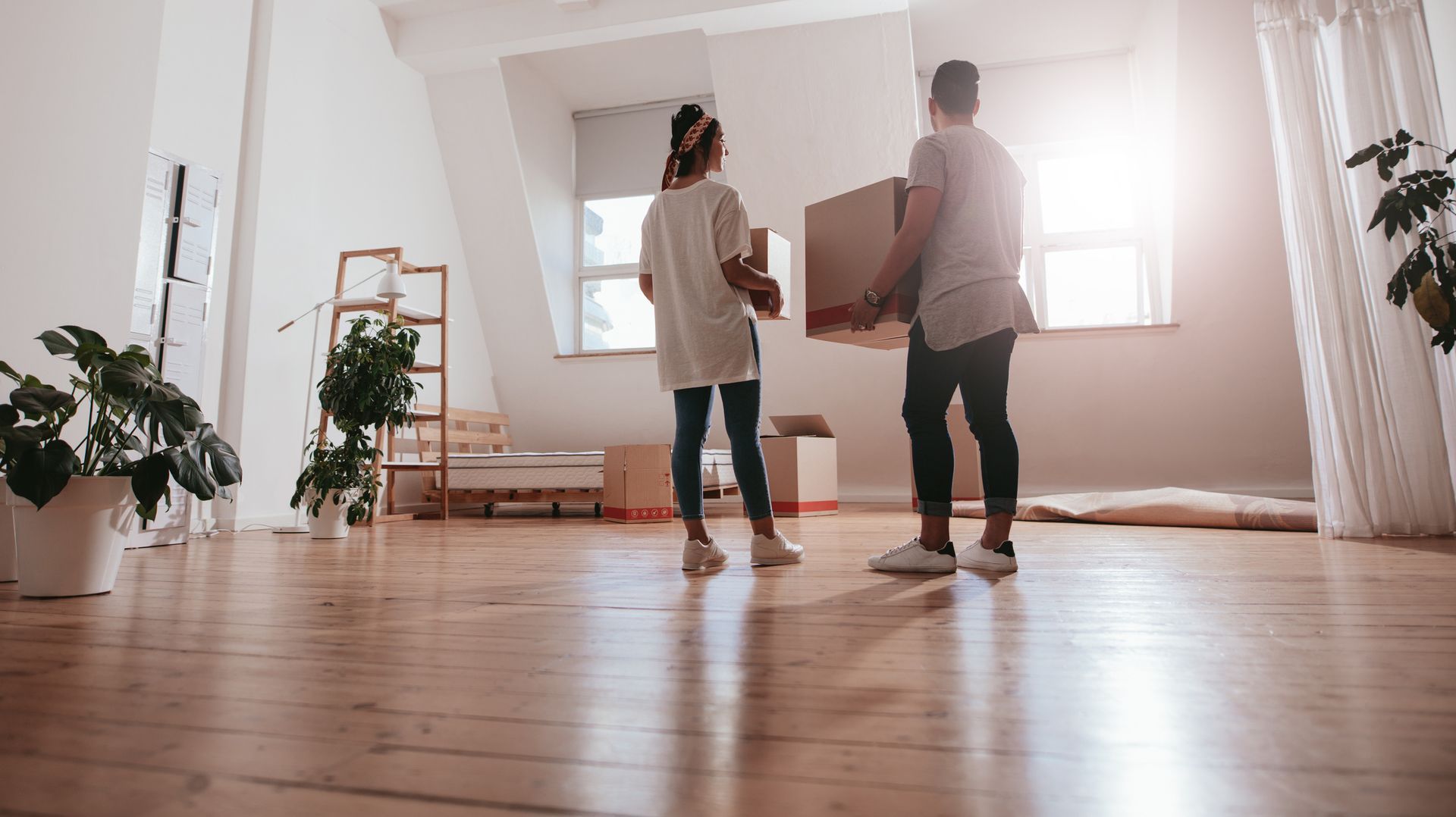 Young couple carrying cardboard box at a new apartment, showcasing local apartment moving by United 