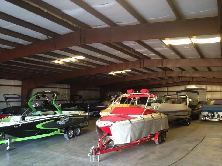 Boats on trailers inside a large storage building with exposed beams.