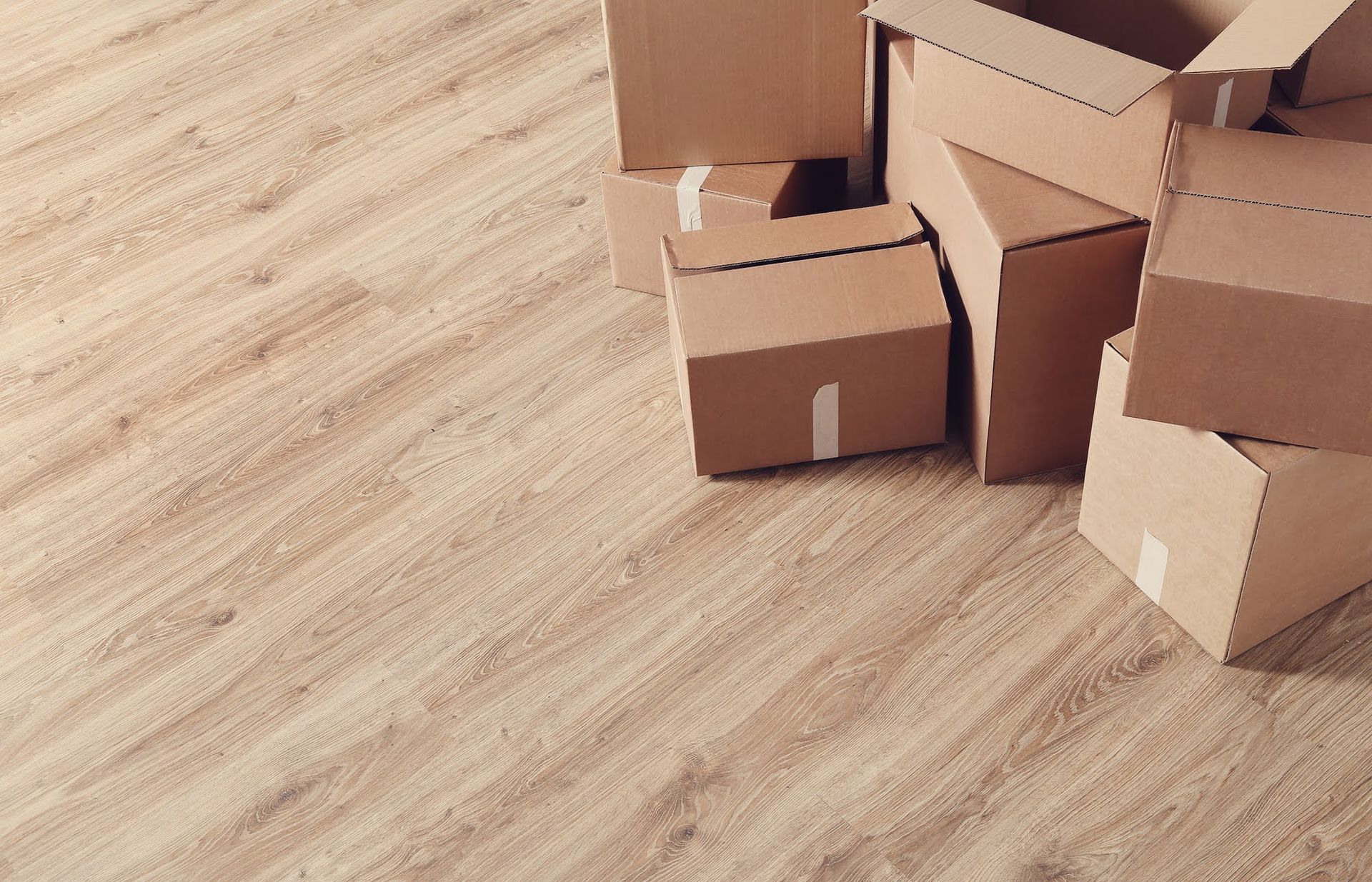 Cardboard moving boxes stacked on a light wood floor.
