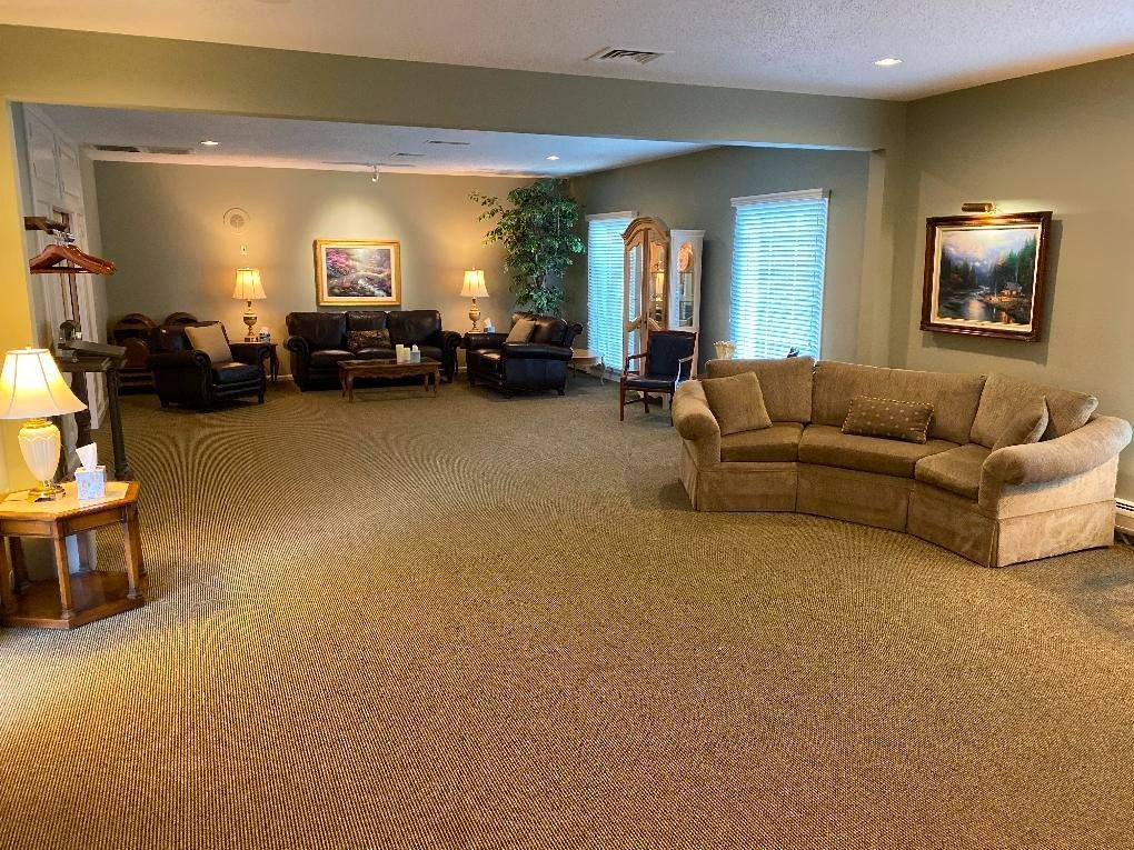An interior room with couches, chairs, lamps, art, and a large carpet.