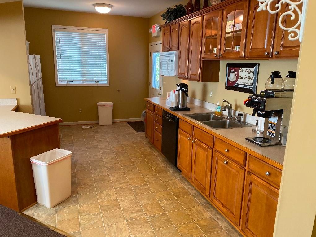 Kitchen with wood cabinets, countertops, appliances, window, and a trash can.