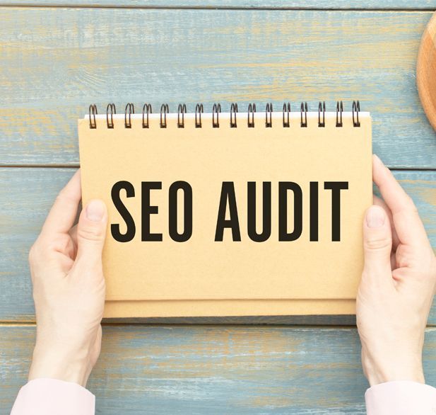 A person is holding a notebook with the words seo audit written on it.