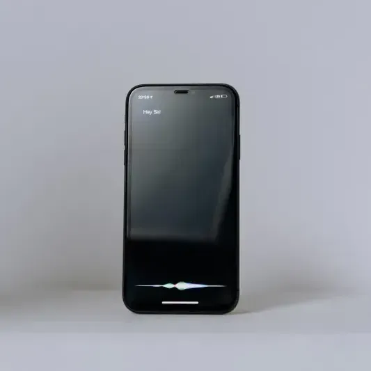 A black cell phone is sitting on a white surface.