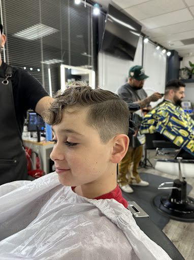 A young boy is getting his hair cut at a barber shop.