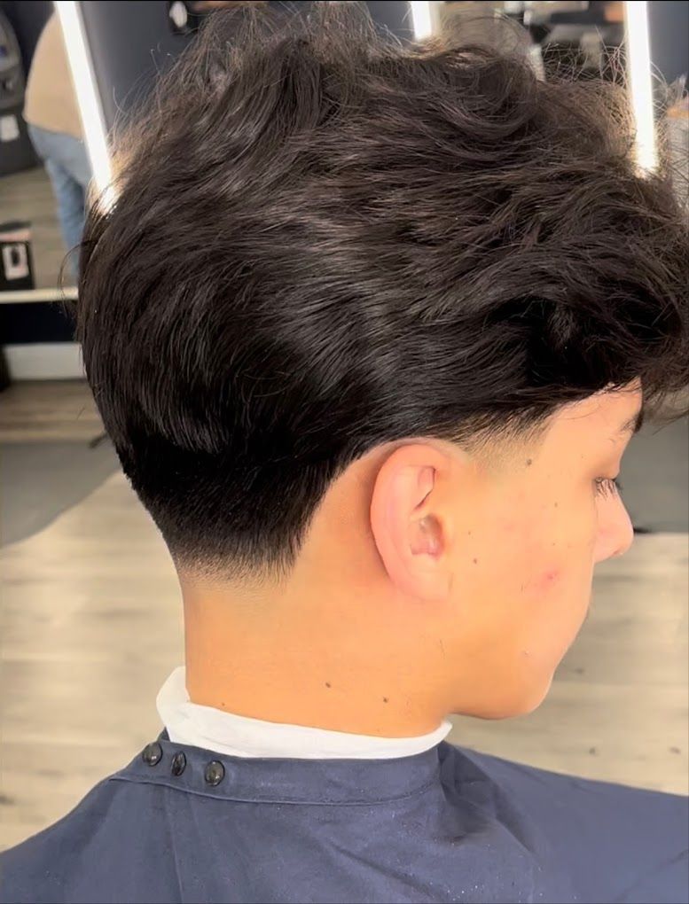 A young boy is getting his hair cut by a barber in a barber shop.