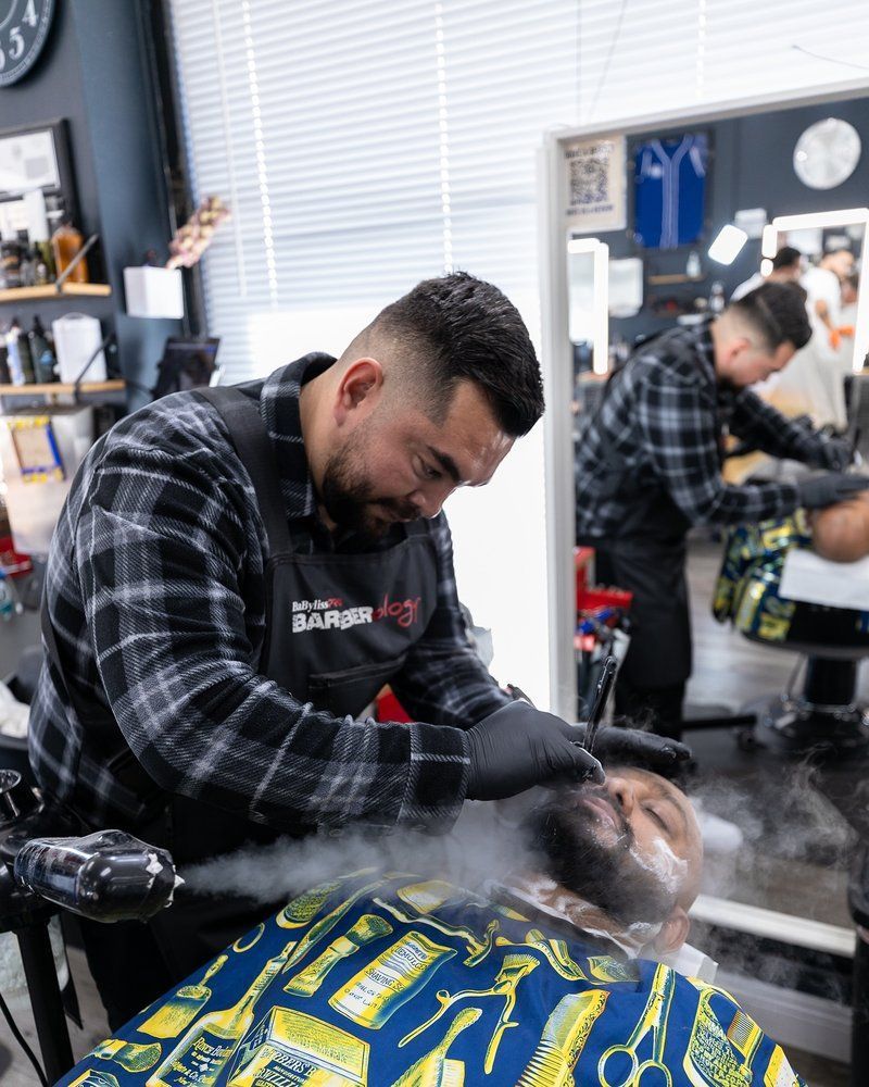 A man is getting his beard shaved by a barber in a barber shop.