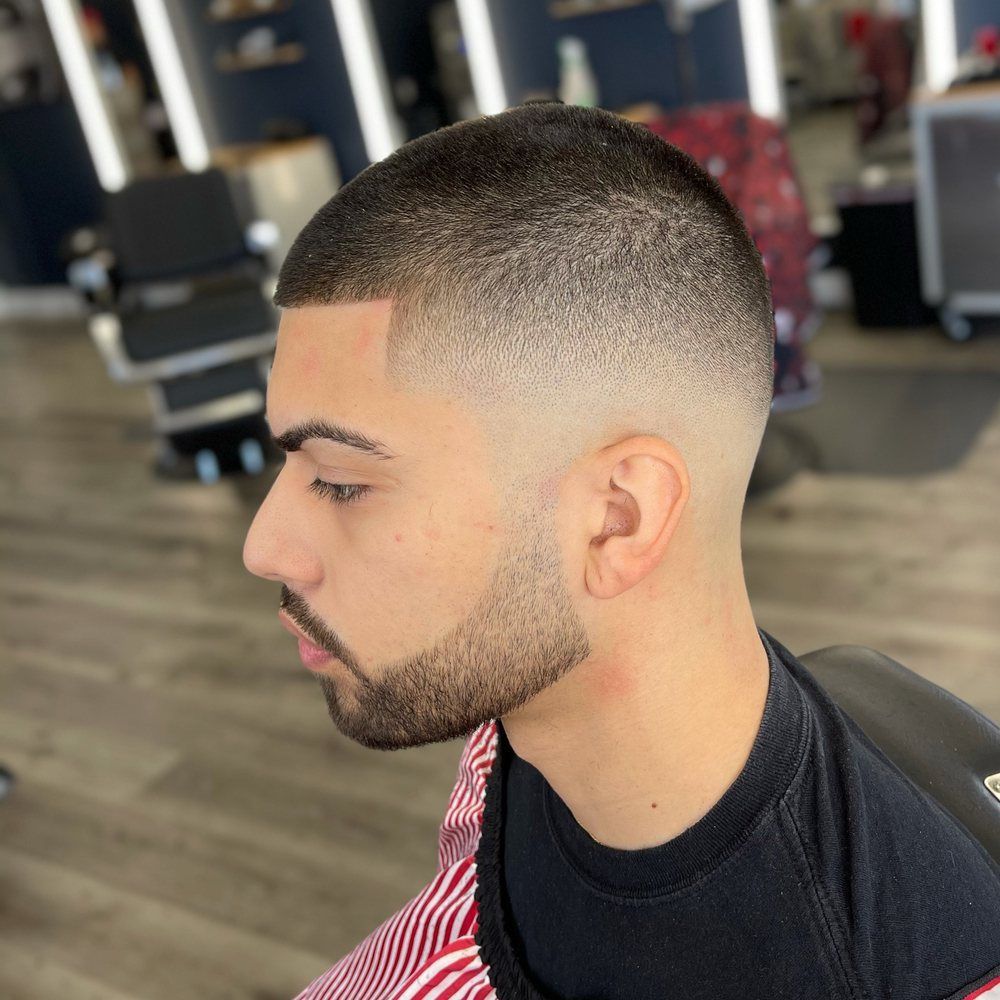 A man with a beard is touching his chin with his hand.
