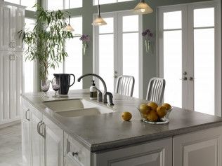 A kitchen with a sink and a bowl of lemons on the counter.