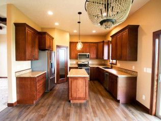 A kitchen with wooden cabinets , stainless steel appliances , and a large island.