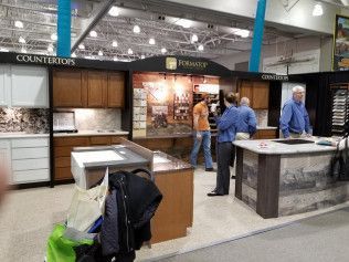A group of people are standing around a countertop display at a kitchen showroom.
