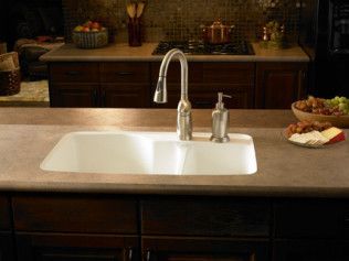 A kitchen sink with a faucet and soap dispenser on the counter.