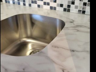 A stainless steel sink is sitting on top of a marble counter.