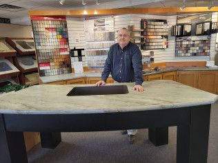 A man is standing next to a large table in a kitchen.