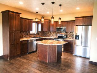 A kitchen with wooden cabinets , stainless steel appliances , and a large island.